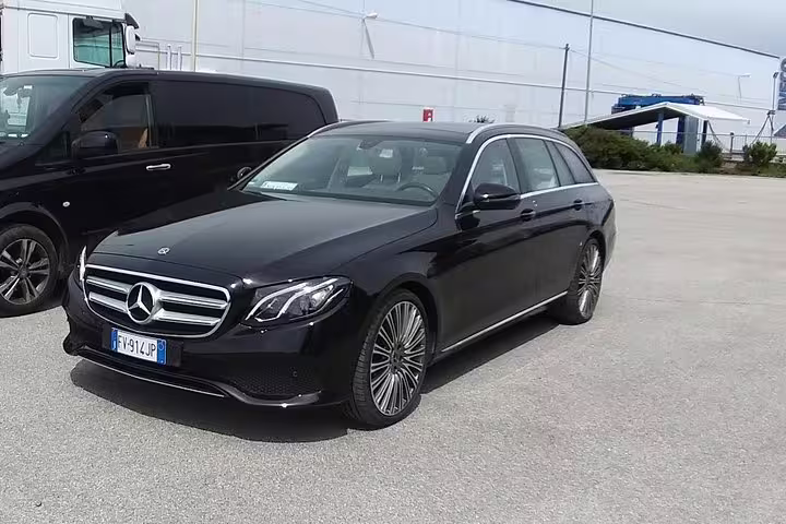 Black Mercedes-Benz E-Class wagon for private transfer service, Italian license plate