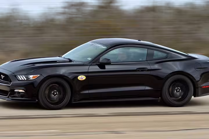 Black Ford Mustang premium car driving at high speed on open road