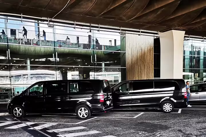 Black private van at Charles de Gaulle Airport curb, ready for pre-booked transfer from CDG to Paris