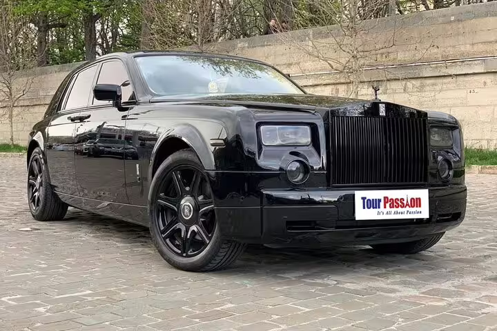 Black Rolls Royce Phantom luxury sedan parked on cobblestone street for private Paris tour