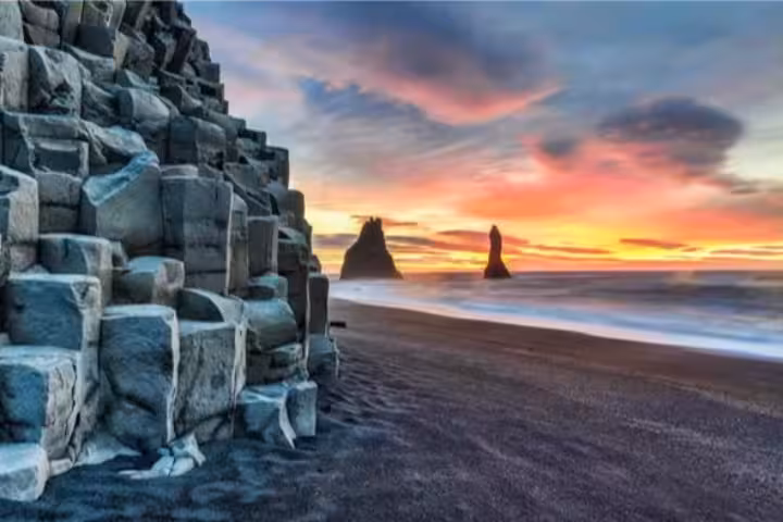 Black sand beach with basalt columns and sea stacks at sunset, Iceland South Coast