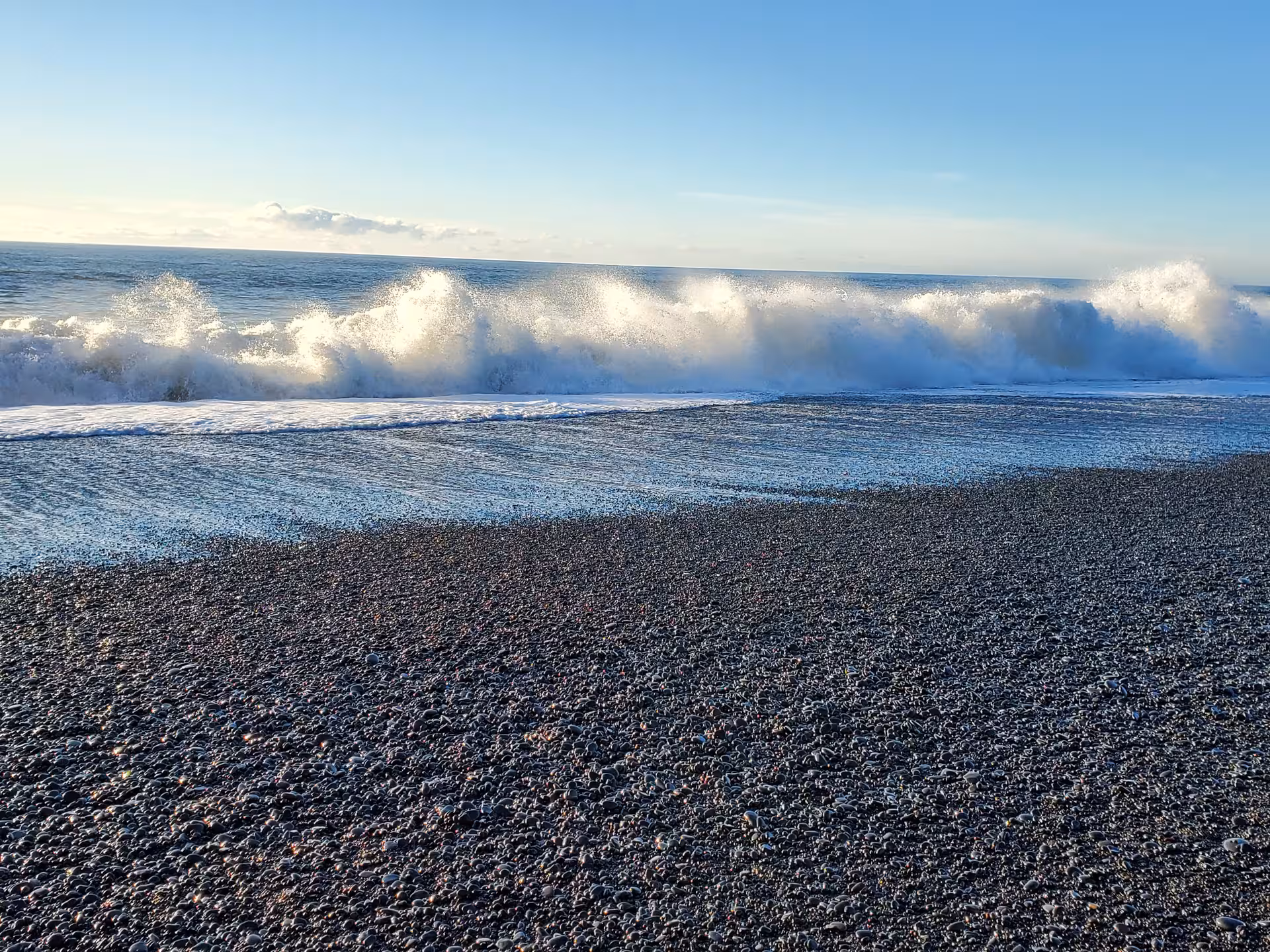 Dramatic ocean waves rolling onto a volcanic black sand beach along Iceland's stunning South Coast tour
