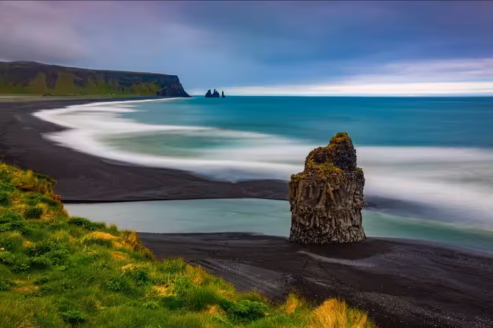Black sand beach with dramatic sea stack and turquoise waves along Iceland's South Coast near Reykjavik