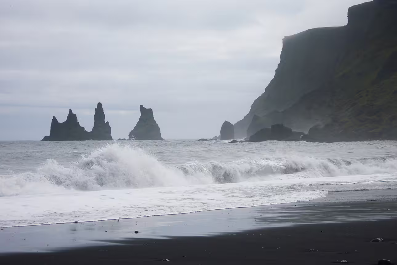 Black sand beach with dramatic sea stacks and crashing waves on Iceland's south coast