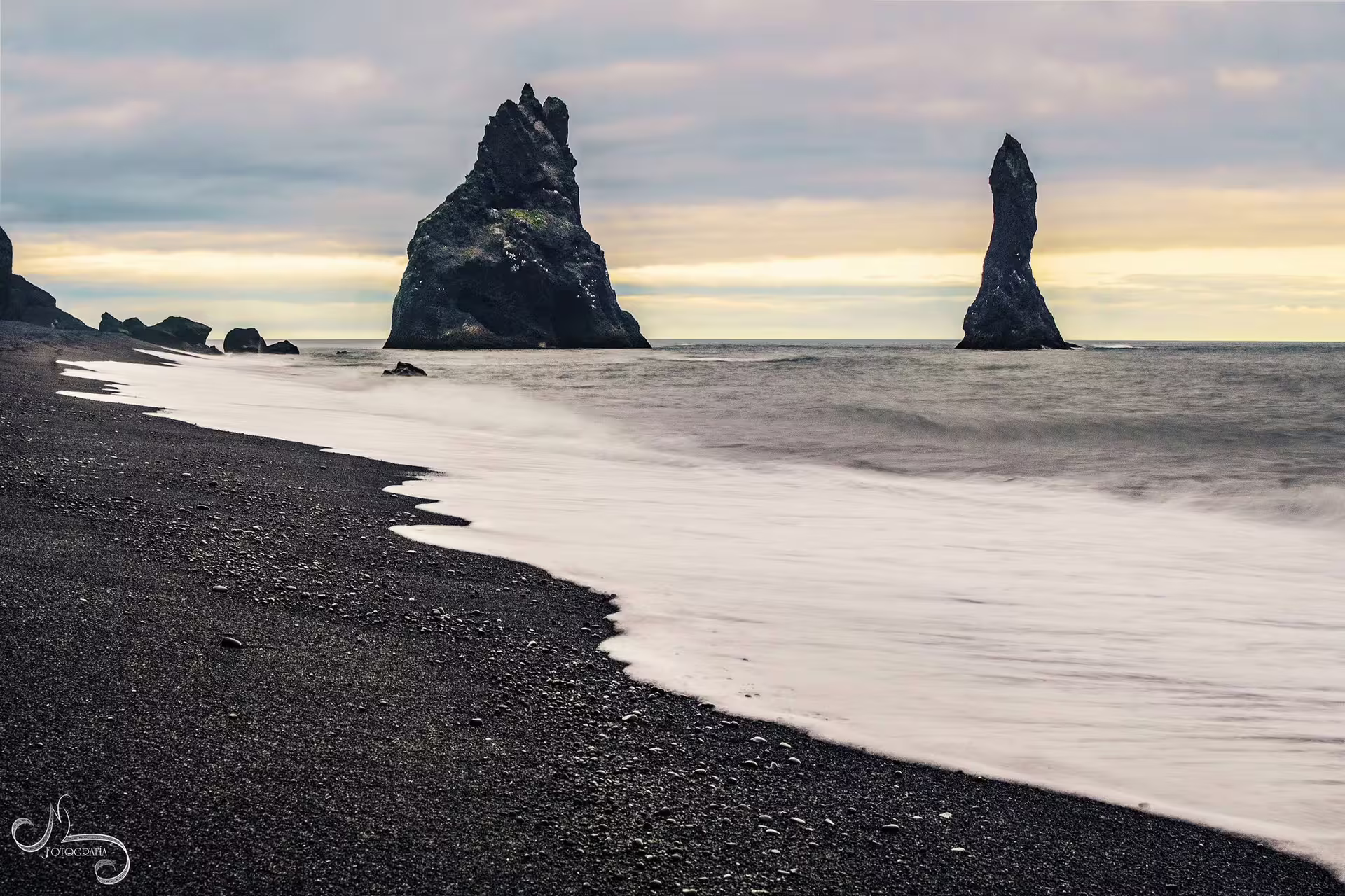 Black sand beach with dramatic basalt sea stacks rising from ocean waves on Iceland's South Coast