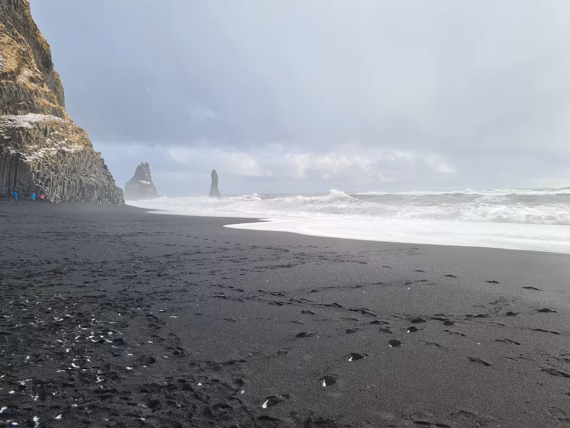 Black sand beach with dramatic rock stacks and crashing waves on Iceland's south coast