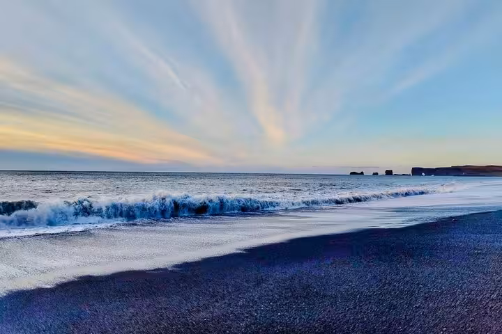 Black sand beach with crashing waves and dramatic sunset sky on Iceland's South Coast