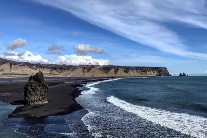 Black sand beach with dramatic rock formations and ocean waves along Iceland's South Coast