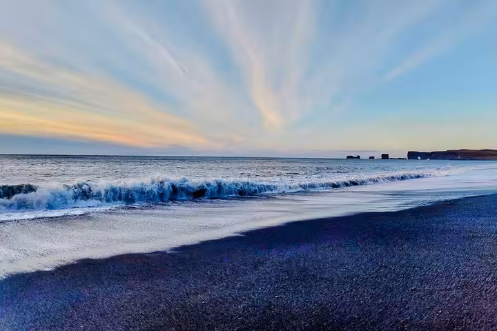 Black sand beach with crashing waves and dramatic sunset sky near Vik, Iceland