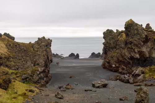 Black sand beach framed by volcanic rock formations on Snaefellsnes Peninsula, Iceland