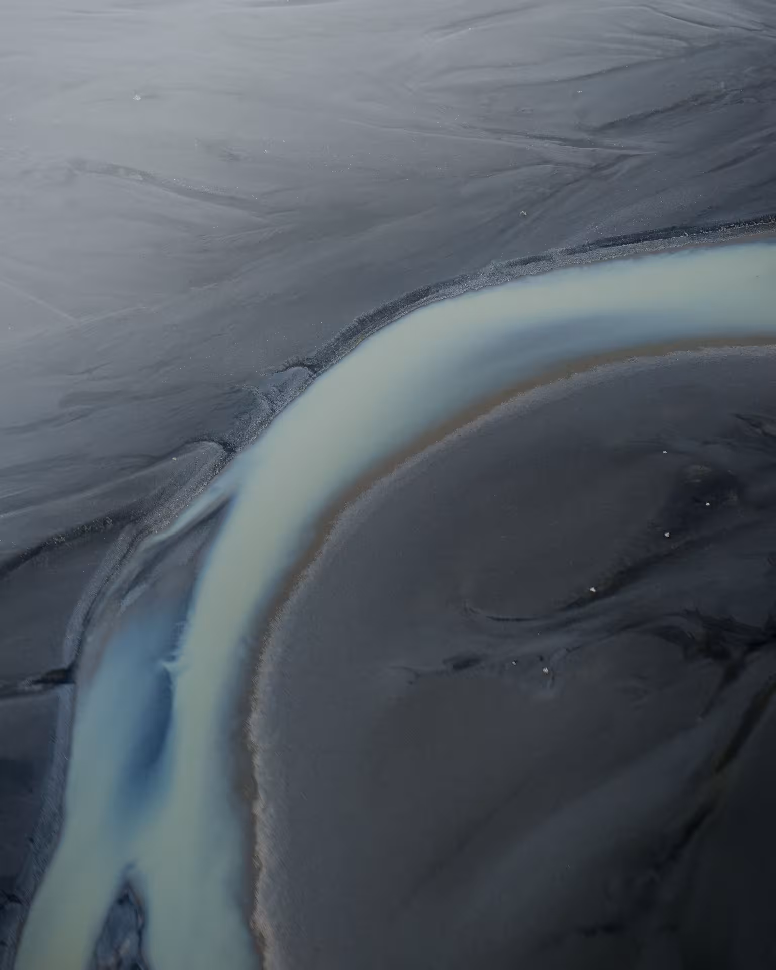 Aerial view of black sand plains with winding glacial meltwater stream from helicopter tour at Skaftafell