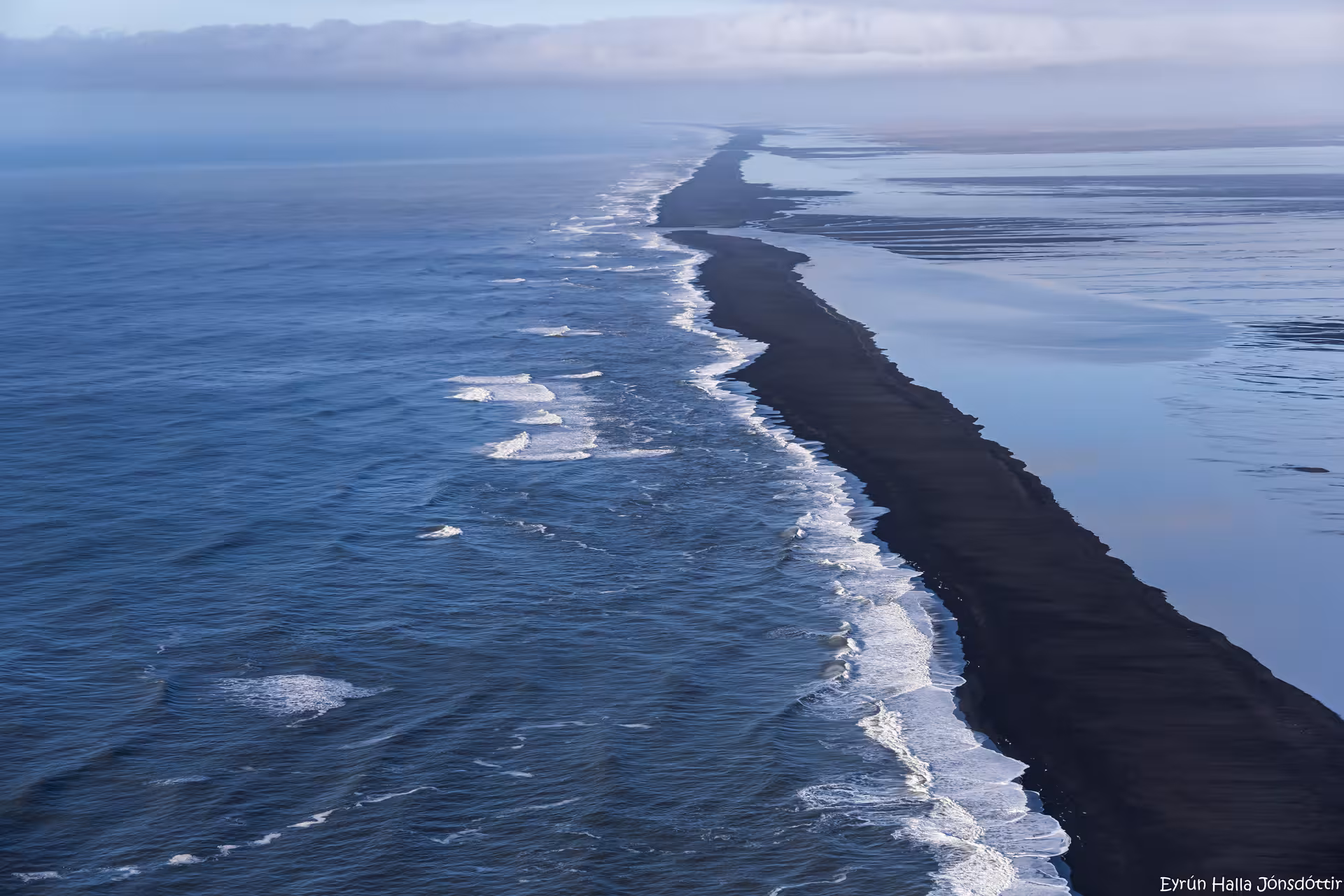 Aerial view of black sand beach peninsula with waves on both sides, Iceland