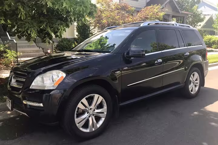 Black Mercedes-Benz GL-Class SUV parked on residential street for private airport transfer