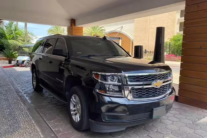 Black Chevrolet Suburban SUV parked at hotel entrance for private airport transfer service