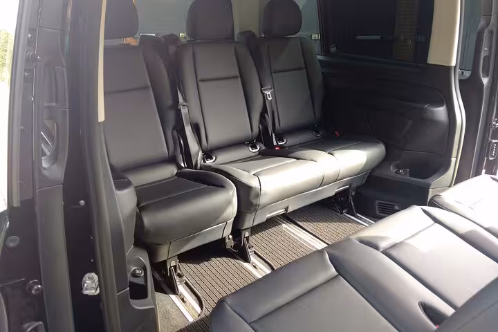 Spacious interior of a black van with plush leather seats, perfect for an 8-hour comfortable journey.