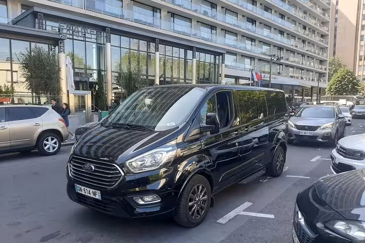 Black Ford Transit van parked outside modern hotel in Paris for private airport transfer