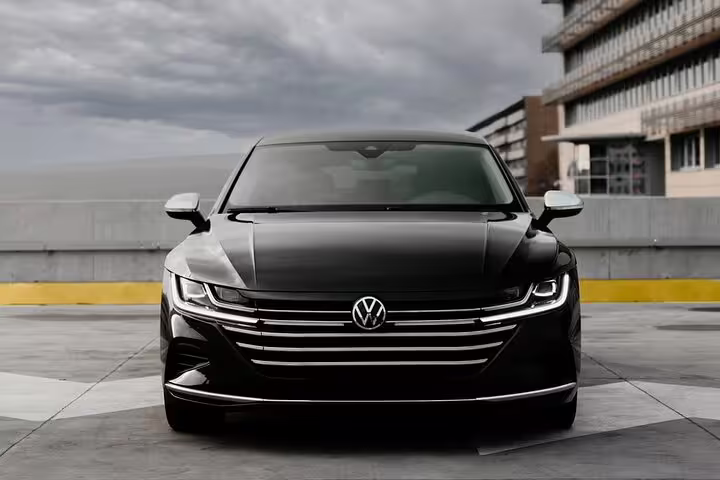 Black Volkswagen Arteon luxury sedan front view parked outdoors under cloudy sky
