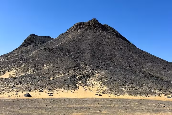 Black Desert volcanic hill in Egypt under blue sky, highlight of a private 2-day Black and White Desert safari