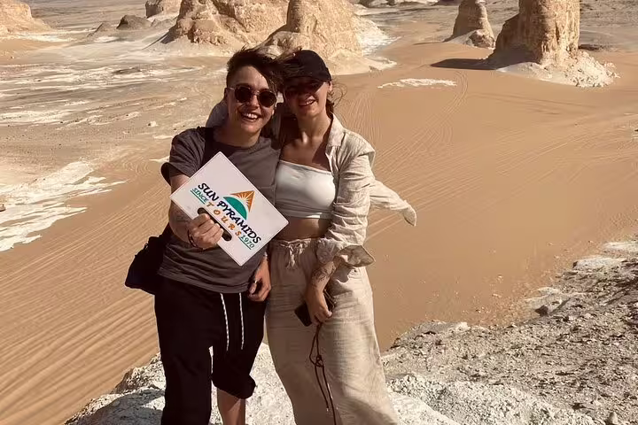 Friends posing with White Desert rock towers on 2-day Black & White Desert jeep adventure tour and camp