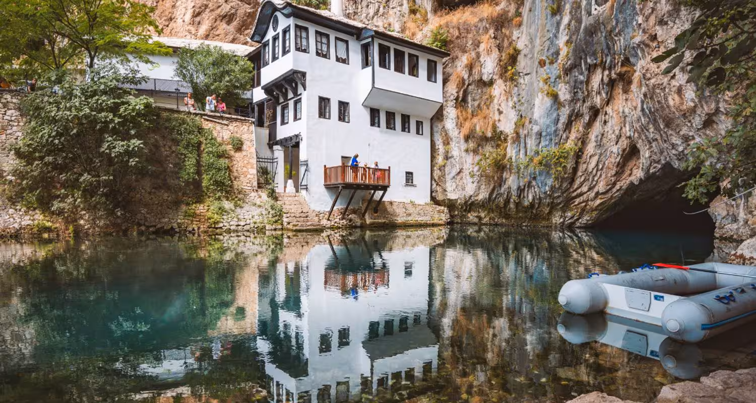 The serene Blagaj Tekke on Buna River, Bosnia, showcasing Ottoman architecture surrounded by cliffs and lush greenery.