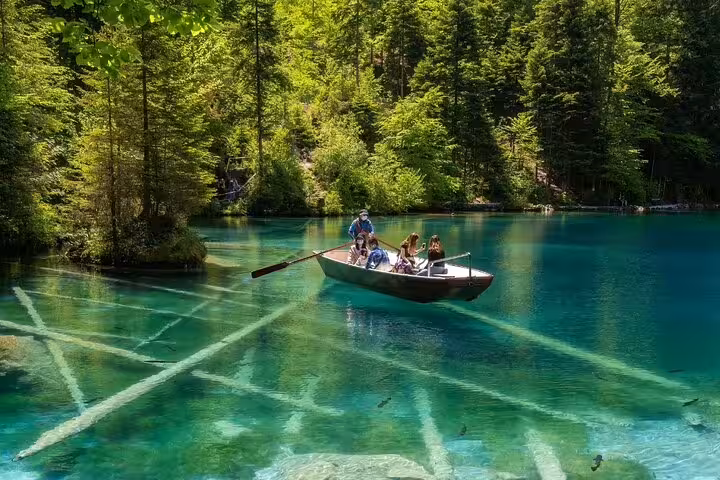 Family enjoying a serene boat ride on the crystal-clear waters of Blausee Lake surrounded by lush greenery.