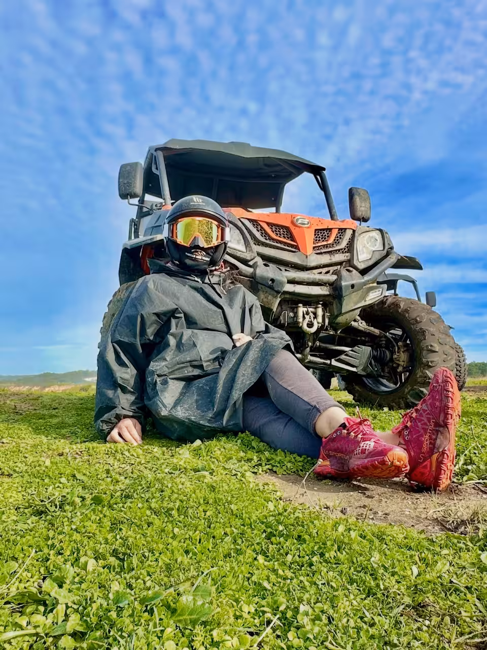 Rider in helmet relaxing on grass beside muddy off-road buggy on Blazing Trails Buggy Tour scenic trail stop