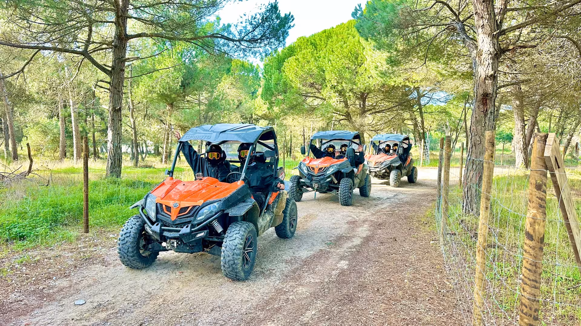 Blazing Trails buggy tour convoy driving a forest dirt track, riders in helmets on off-road UTV adventure