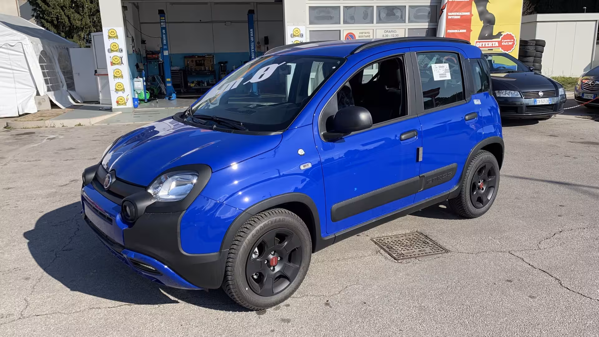 Blue car parked outside a service station in Calasetta, ideal for convenient and budget-friendly car rentals.