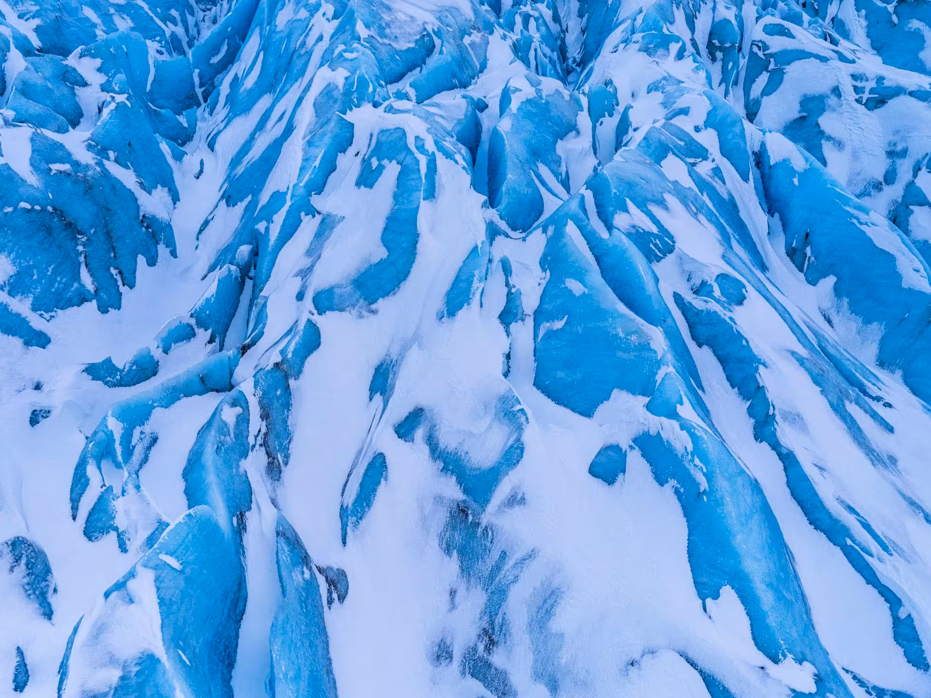 Aerial view of blue glacier ice formations with snow in Iceland