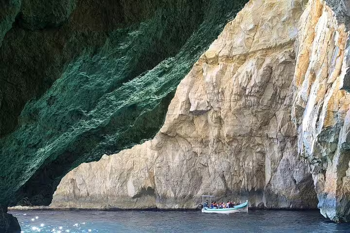 Small boat tours the stunning Blue Grotto, showcasing Malta's dramatic sea caves and azure waters.