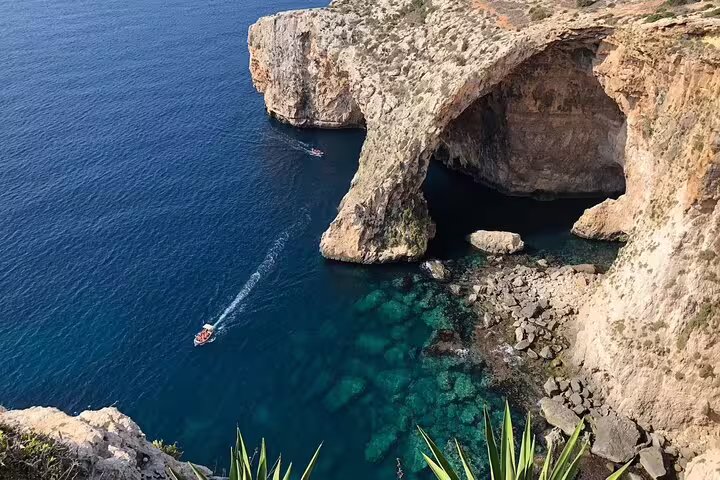 Scenic view of the Blue Grotto cliffs and azure waters with a small boat navigating the tranquil sea.