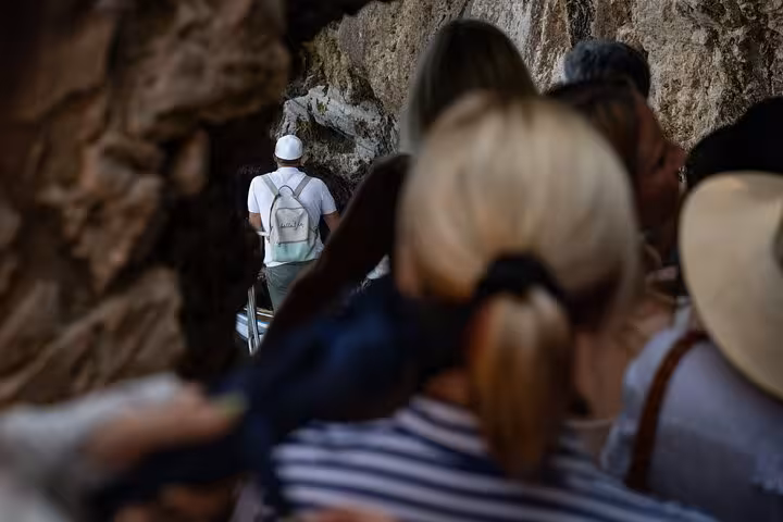 Visitors enter a rocky passage on the Blue Grotto tour, highlighting the adventure of the iconic Naples sights.