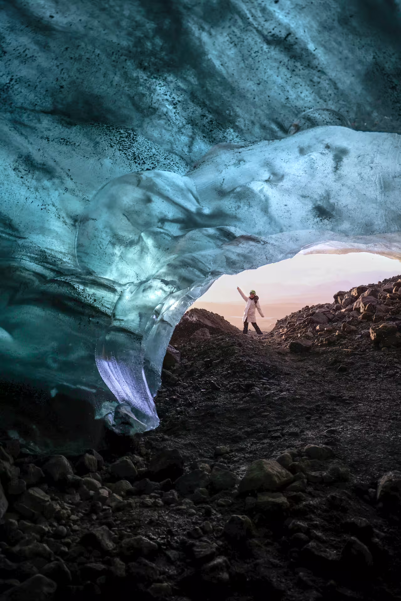 Adventurer standing at the entrance of a breathtaking blue ice cave glacier arch on a 5-hour winter hike tour