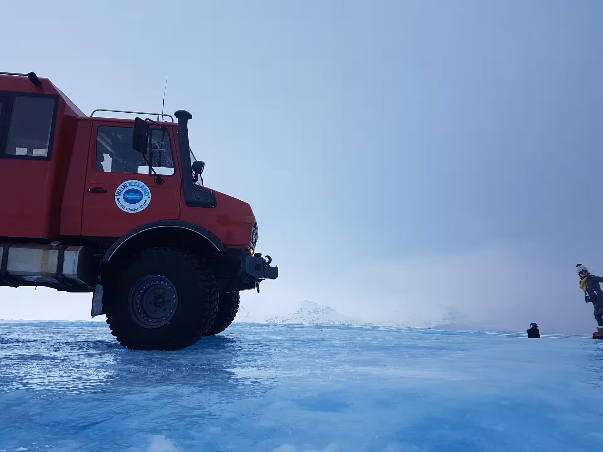 Red Blue Iceland super jeep on Vatnajokull glacier ice surface with misty mountains in background
