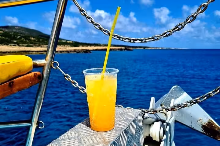 Refreshing orange drink on deck during Blue Lagoon Akamas boat cruise from Paphos with sea views