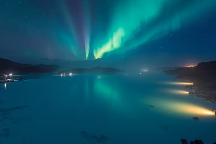 Aurora borealis dancing over Blue Lagoon geothermal spa waters at night in Keflavik Iceland