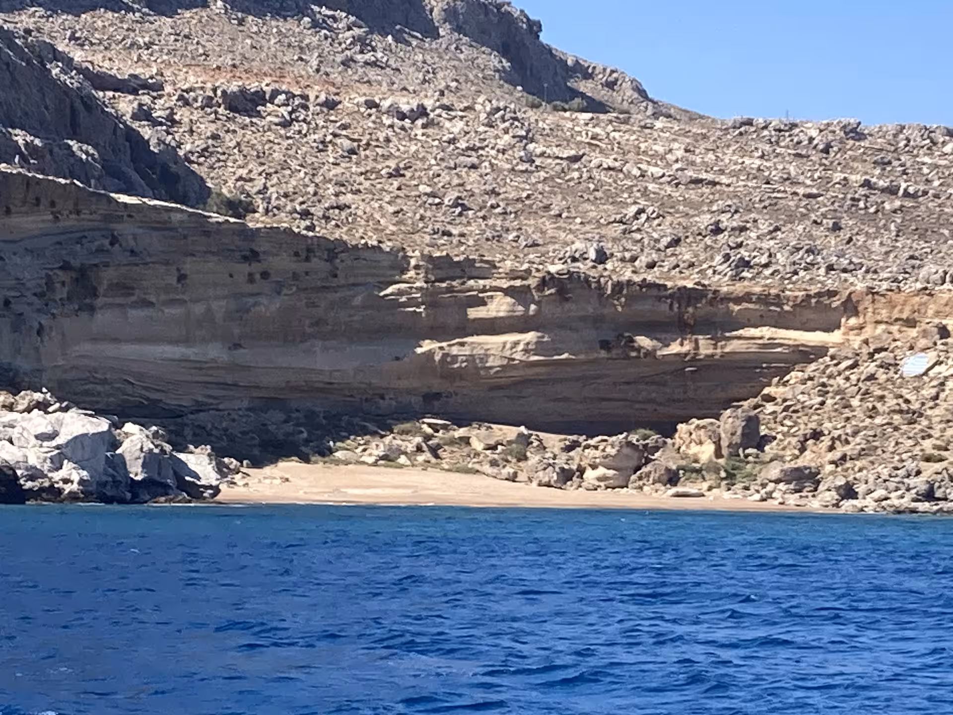 Rocky cliffs and sandy cove with deep blue sea on Discover Blue Lagoon Axopar 25 CT boat tour