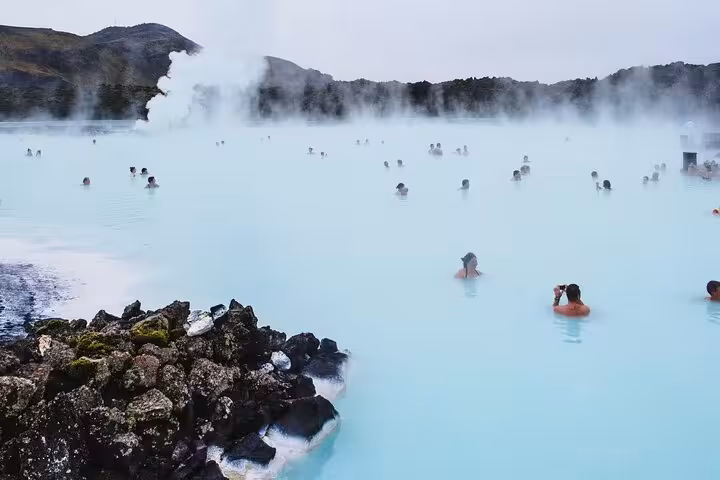 Tourists bathing in the milky blue geothermal waters of Iceland's Blue Lagoon with steam rising