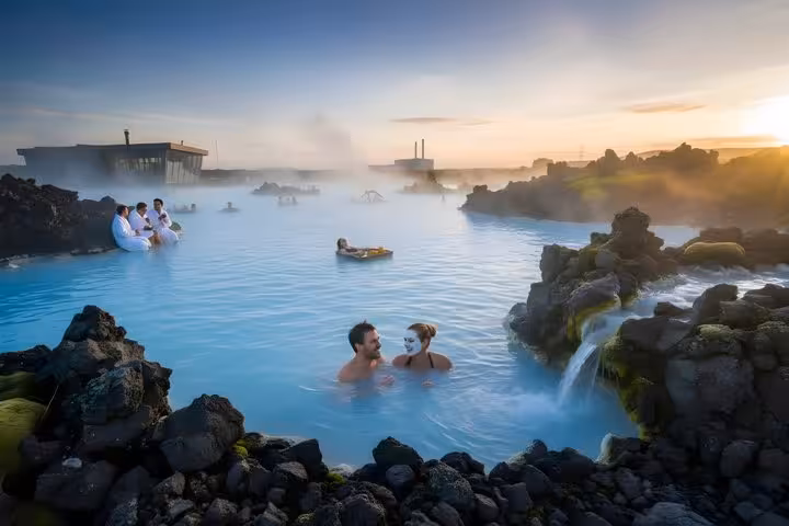 Couples and guests bathing in the steaming blue geothermal waters of Blue Lagoon Iceland at sunset