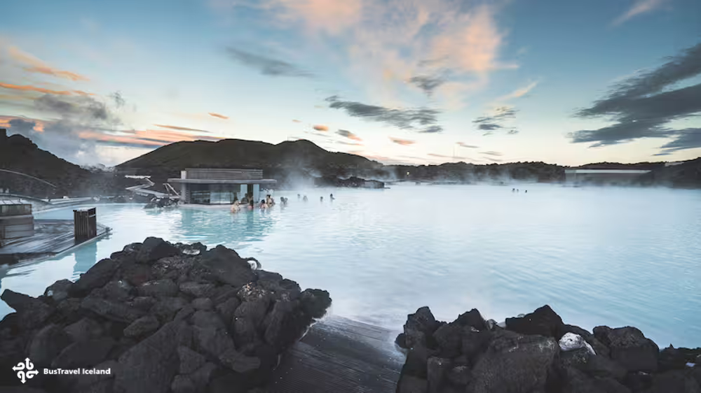 Steaming milky-blue geothermal waters of the Blue Lagoon in Iceland at sunset with volcanic rocks