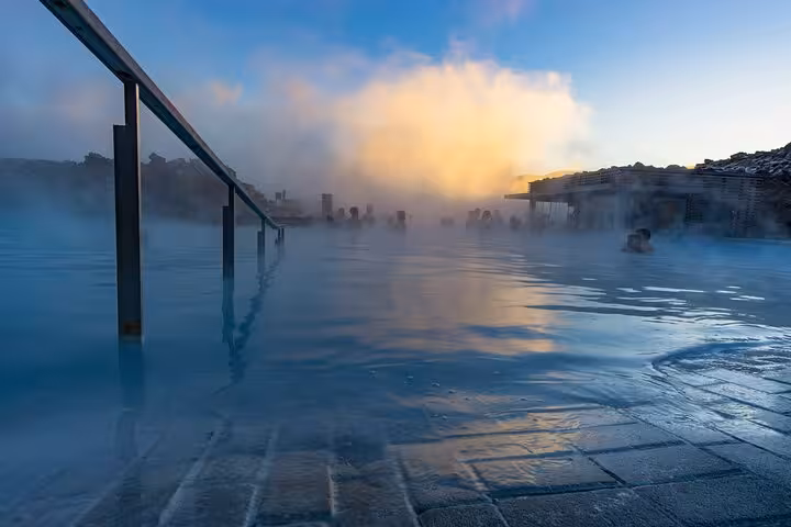 Steaming Blue Lagoon geothermal pool at dawn with misty blue waters and golden clouds in Iceland