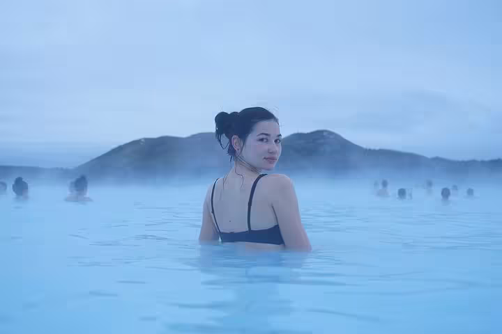 Woman relaxing in the steamy blue geothermal waters of Blue Lagoon, Iceland, with misty mountains in background