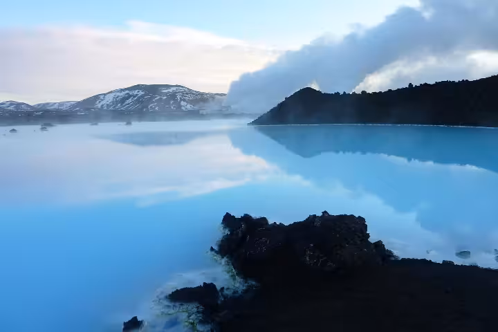 Blue Lagoon geothermal pool with milky blue waters, steam rising, and black lava rocks near Keflavik, Iceland