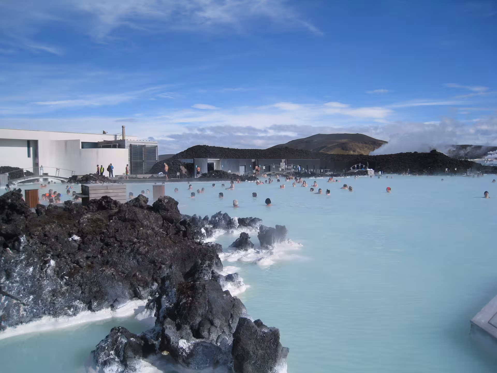 Milky blue geothermal waters of the Blue Lagoon in Iceland with volcanic lava rocks and bathers