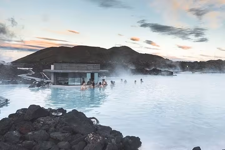 Visitors bathing in the milky blue geothermal waters of the Blue Lagoon, Iceland, with steam rising at dusk