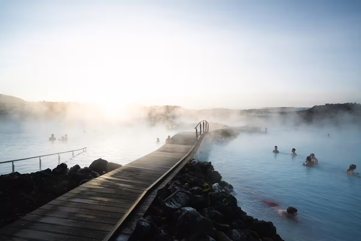 Steaming Blue Lagoon geothermal pool in Reykjavik with wooden boardwalk and bathers in milky blue water