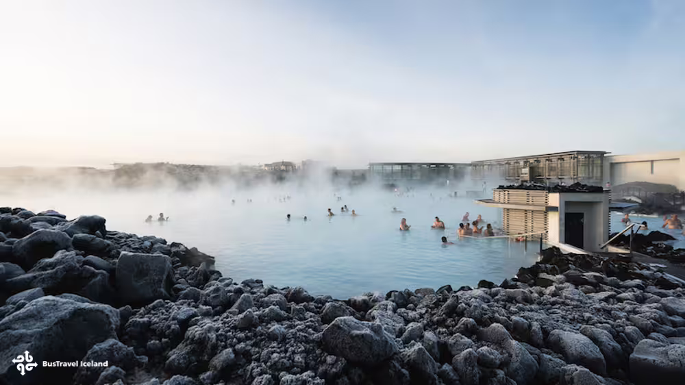Steaming Blue Lagoon geothermal pool with bathers surrounded by lava rocks in Iceland