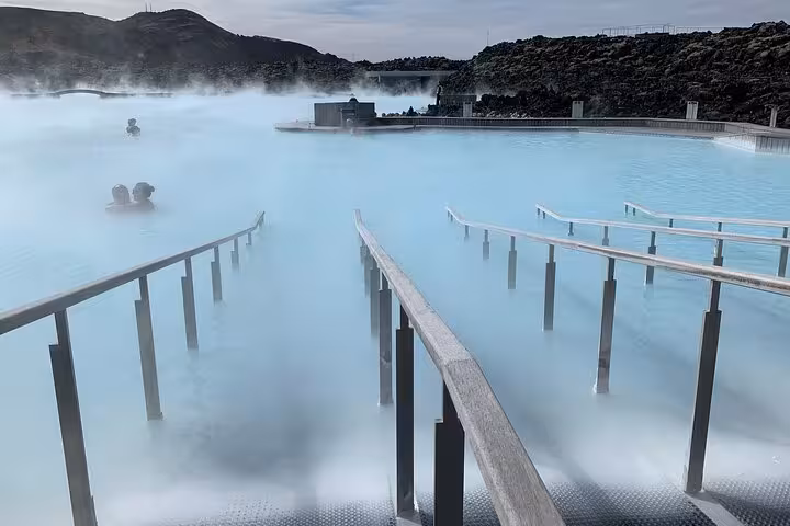 Steaming milky blue geothermal waters of the Blue Lagoon in Iceland with bathers and lava rock backdrop