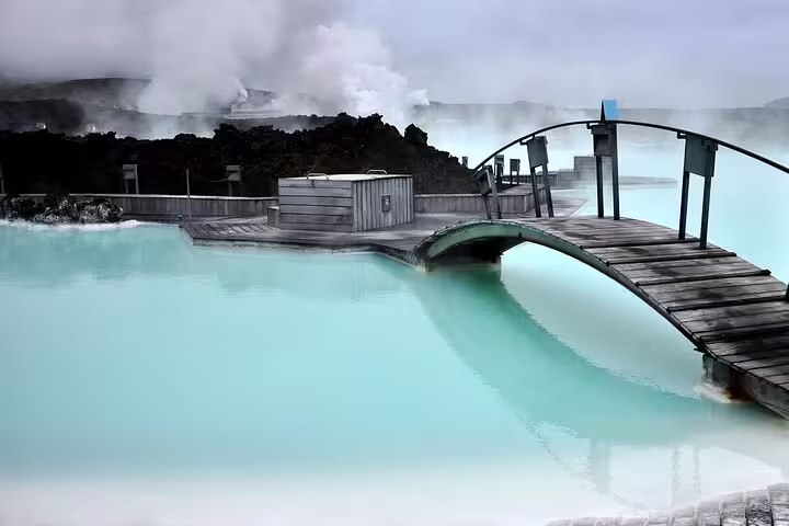 Milky blue geothermal waters of Blue Lagoon Iceland with wooden bridge and steam rising in background