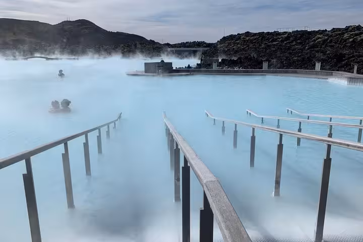 Steaming milky blue geothermal waters of Blue Lagoon spa in Iceland with handrails and bathers